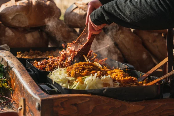 木製のキッチンスパチュラを持つシェフは 屋外市場で大きなフライパン 熱い食べ物で野菜を攪拌します クラクフの伝統的なポーランド料理の上に白い蒸気 — ストック写真