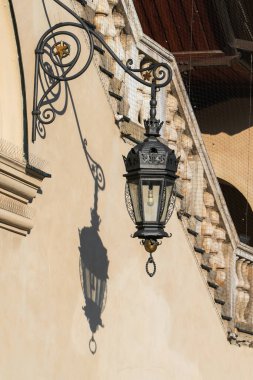 Klasik sokak lambası Krakow 'daki eski bir evin duvarına uzun bir gölge bırakıyor.
