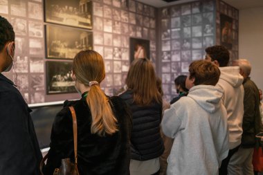 Tıbbi maskeli siyahi bir adamın yanındaki genç beyaz kadın Avrupa 'da karışık bir turist grubu, etnik çeşitlilik ve hoşgörü içinde müzedeki bir rehberi güvenle dinliyor.