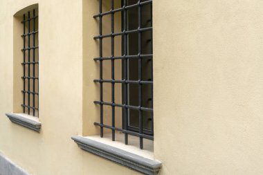 Bir manastır duvarının iki penceresinde klasik siyah metal dövülmüş sarı alçı, seçici odak, kenar görüş, kopyalama alanı