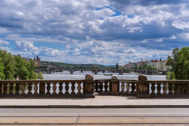 Güneşli bir günde Prag, Çek Cumhuriyeti 'ndeki Vltava nehrinde tatilcilerle birlikte keyif botları ve su bisikletleri, gökyüzünde beyaz bulutlu bir uçak, kıyıda uzun yeşil ağaçlar, Avrupa turizmi