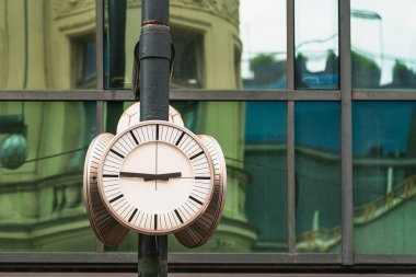 Şehir saatine göre saat 14: 45. Geçmişten kalma eski bir evin duvarının yansımasının donduğu pencere camlarının arka planına karşı yeşil metal destekli.