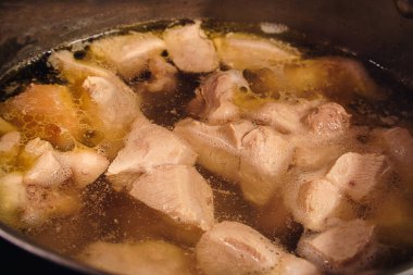Ocaktaki çelik bir tencerede et suyuna yakın plan, tavuklu et parçaları tencerede kaynatılır, çorba için sıcak çorba manzarası.