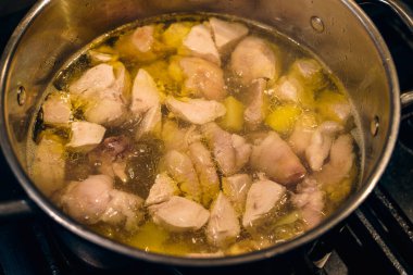 Ocaktaki çelik bir tencerede et suyuna yakın plan, tavuklu et parçaları tencerede kaynatılır, çorba için sıcak çorba manzarası.