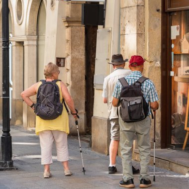 Sırt çantalı ve ellerinde İskandinav bayramı için yapışmış üç emekli güneşli bir yaz gününde Krakow 'dan geçiyor. Aktif emeklilik yaşam tarzı, güçlü dostluk
