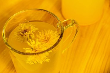 Dandelion tea in a glass cup on a uniform background, a natural product from Taraxacum protects against diseases, dandelion herbal tea improves cellular health, helps in weight loss