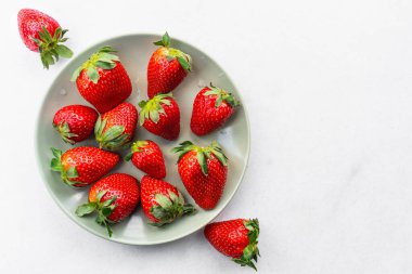 Red ripe strawberries in a light green bowl, light background, top view, healthy food, natural vitamins.Copy space