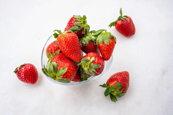 Red ripe strawberries in a light green bowl, light background, top view, healthy food, natural vitamins.Copy space