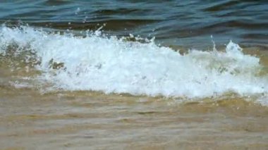 Sandy beach on the Baltic Sea in Gdansk, splashes of waves near the shore, close-up, splashes of waves shining in the sun, summer holidays at the sea