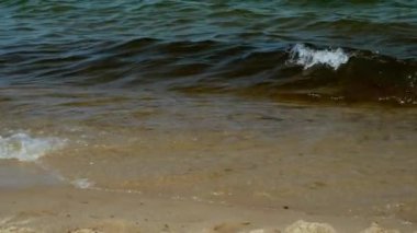 Sandy beach on the Baltic Sea in Gdansk, splashes of waves near the shore, close-up, splashes of waves shining in the sun, summer holidays at the sea
