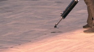 A worker repairs paving slabs, fills small cracks with a special compound to prevent further destruction of the road surface. Close-up