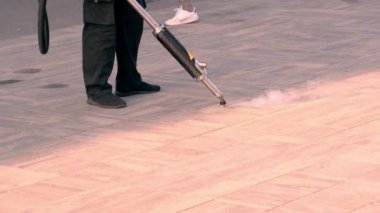 A worker repairs paving slabs, fills small cracks with a special compound to prevent further destruction of the road surface. Close-up