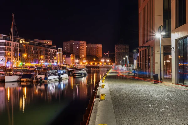 Night illumination of the embankment of the old town in Gdansk, reflections of the embankment lanterns on the surface of the water, tourist attractions in Poland