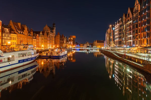 Night illumination of the embankment of the old town in Gdansk, reflections of the embankment lanterns on the surface of the water, tourist attractions in Poland