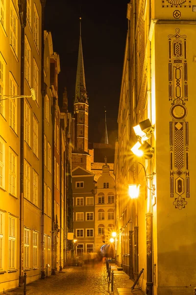 Night illumination on an old medieval street in the historical center of Gdansk, ghosts of human figures on a narrow street, Poland tourist attractions