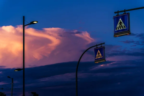 Street lighting LED lamp on electric pole illuminates the street against white cloud in the sky after sunset, crosswalk road signs and electric poles in Italy, sunset sky background image