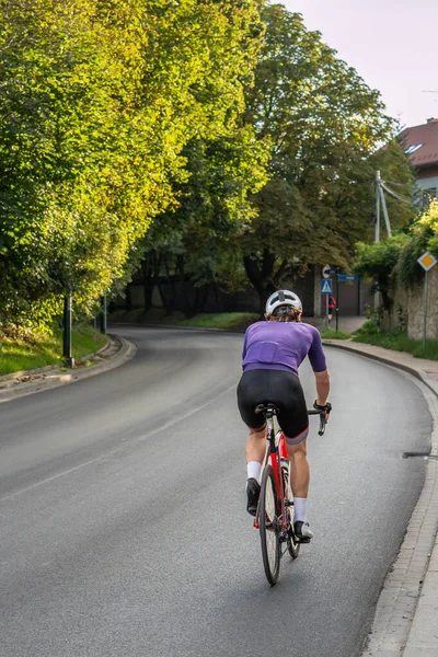 Sports background. Athletic man cycling in sportswear on an asphalt road on a summer evening, evening cycling, healthy lifestyle