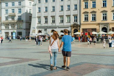 Güneşli bir yaz gününde eski kasabada el ele tutuşan çiftler, geleneksel genç çiftler, Krakow 'da turistler, yakın ilişkiler, aşk