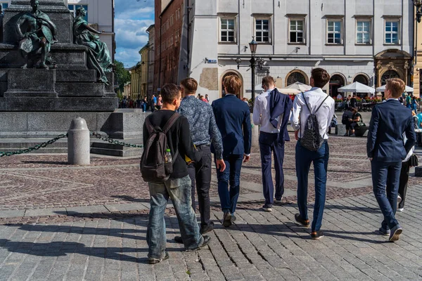 A group of high school students walk in the center of an old European city on a sunny autumn day, back to school in September, schoolchildren in Krakow, Poland
