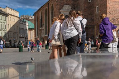 Bir grup ortaokul öğrencisi, güneşli bir sonbahar gününde eski bir Avrupa şehrinin merkezinde, Eylül 'de okula, Polonya' nın Krakow kentindeki okul çocukları