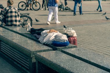 Genç bir kız güneşli bir yaz gününde Krakow 'daki pazar meydanında mermer bir bankta uyur. Yoldan geçenler arasında el bagajı seyahat valizi, uyuyan bir turistin yanında.
