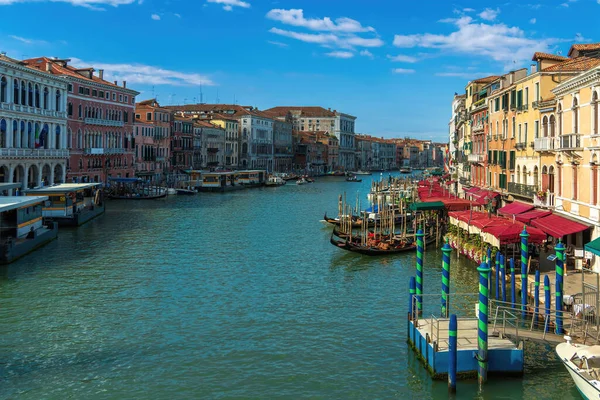 Motor boats and gondolas on a wide canal street in Venice, vintage houses and summer restaurants on a Venetian street on a sunny morning, houses on the banks of a canal in the city of Venice