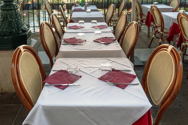 Summer restaurant tables covered with white tablecloths, empty glasses, knives, forks and glasses on the clean tables of a street cafe on the street of the city of Venice, Italy