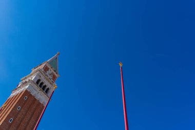 Venedik, İtalya 'daki St. Mark Meydanı' ndaki çan kulesi açık gökyüzüne gidiyor. Bir jet uçağının uçtuğu ve ayın hilal şeklinin göründüğü yere. Çan kulesinin tepesinde iki işçinin figürleri var.