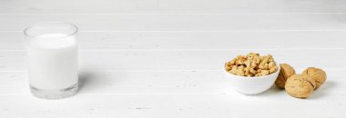 Beyaz ahşap arka planda ceviz ve fındıktan süt. Sebze proteini, vitamin ve yararlı amino asit içeren ürünler. Boşluğu kopyala.