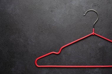 Koyu beton arka planda kırmızı ceket askıları var. Boşluğu kopyala