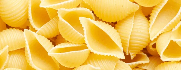 Rå conchiglie pasta. Matbakgrund. En ingrediens för traditionell italiensk mat. Närbild — Stockfoto
