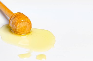 Tahta kaşıkla taze bal döküldü. Beyaz arka plan. Boşluğu kopyala