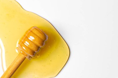 Tahta kaşıkla taze bal döküldü. Beyaz arka plan. Boşluğu kopyala