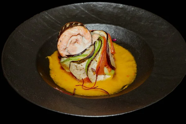 Balık tabağı: siyah arka planda sebze ve sos ile kızarmış ya da fırında somon.