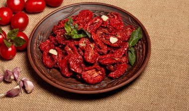 Dried tomatoes with basil garlic and spices in a clay bowl