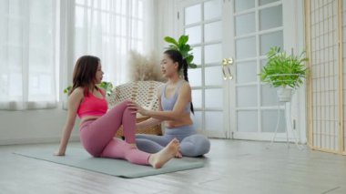 Asyalı kadın yoga öğretmeni öğrencilere temel egzersizleri, egzersiz kavramlarını ve sağlığını öğretiyor.