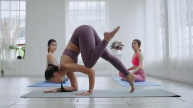 Asyalı kadın yoga öğretmeni öğrencilere temel egzersizleri, egzersiz kavramlarını ve sağlığını öğretiyor.