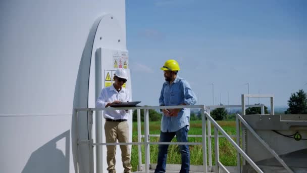 2人のエンジニアが風力発電プロジェクトについて話し合い 風力タービンの分野で働く クリーンエネルギーの概念 再生可能エネルギー 世界を救う — ストック動画