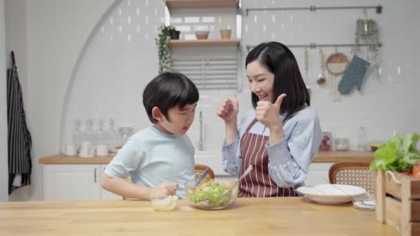 家のキッチンルームでアジアの幸せな家庭料理 母親と息子がサラダを作るのを手伝っています 家族関係 — ストック動画