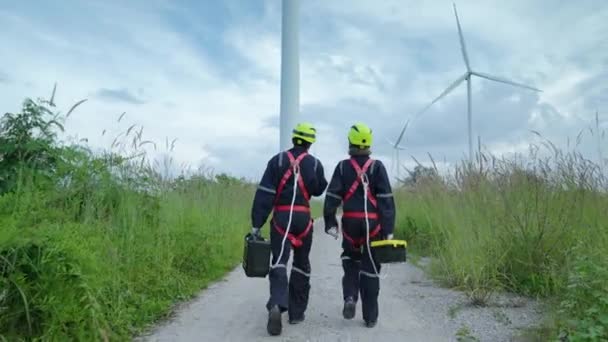 風力タービン クリーンエネルギーコンセプト 再生可能エネルギーの動作を確認するために 世界を救うために 風力タービンに歩いて高さで働く安全装置の2人のメンテナンスエンジニア — ストック動画