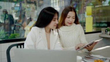 İki Asyalı kadın iş ortağı, bir internet kafede sohbet ediyorlar, yemek işi konsepti teknolojik kolaylıkla birleştirilmiş, yeni nesil yaşam tarzı.