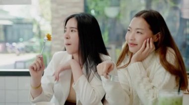 İki güzel Asyalı bayan arkadaş, bir kafede yemek yemek ve sohbet ederken, şehir yaşam tarzı konsepti, tatil rahatlaması.