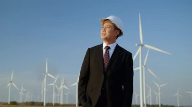 Rüzgar türbini sahasında, iş adamı gururla gülümsüyor. Rüzgâr enerjisi projesine. Temiz, yenilenebilir, yeşil bir enerji..