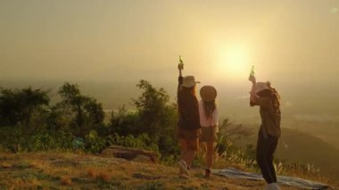 Kız arkadaş grubu Asyalı blogcu akşam günbatımında doğanın güzelliğinin tadını çıkarıyor ve sosyal medyadaki arkadaşlarına, özgürlük konseptine hava atmak için aksiyon kameralarından video çekiyor.