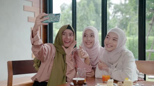 一群在餐馆吃饭的穆斯林女孩正在用手机在社交媒体上与朋友在线聊天 并在斋月结束后与朋友出去喝酒吃饭 — 图库视频影像
