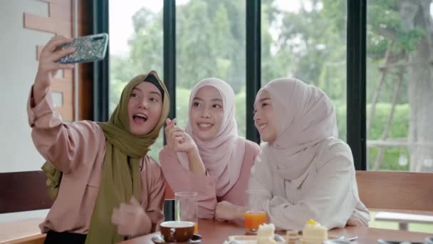 一群在餐馆吃饭的穆斯林女孩正在用手机在社交媒体上与朋友在线聊天 并在斋月结束后与朋友出去喝酒吃饭 — 图库视频影像