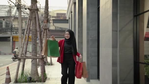 若いイスラム教徒の女性は買い物から戻った後 喜んで路上で買い物袋を運びます — ストック動画