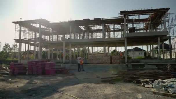 エンジニア 建築家 フォアマン 建設労働者で構成されるアジアの建設チーム 様式及び日程により完成予定の建物の建設の相談及び計画 — ストック動画