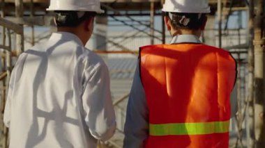 Dış inşaat sahalarında, Asyalı mühendisler ve mimarlar binanın yapım çalışmalarının form ve çizelgesine göre tamamlanması planlanıyor..