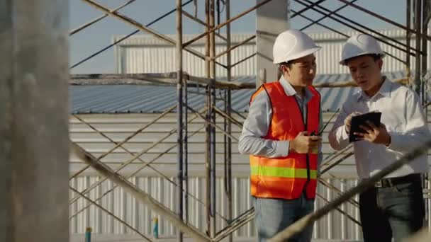 屋外の建設現場では アジアのエンジニアや建築家フォームやスケジュールに従って完成する建物の建設をコンサルティングし 計画しています — ストック動画